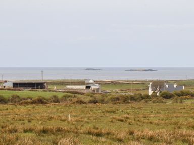 A rural landscape with farm buildings grass fields and the sea in the background at Cherry Blossom Cottage in Quilty County Clare