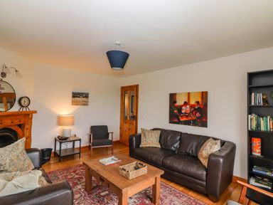 A living room with sofas a coffee table a bookshelf and artwork on the wall at Cherry Blossom Cottage in Quilty County Clare