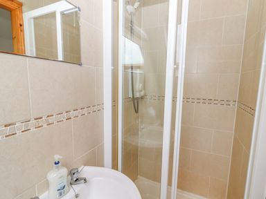 A bathroom with a sink and a shower enclosure with tiled walls at Cherry Blossom Cottage in Quilty County Clare