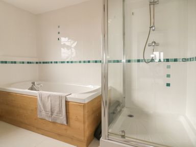 A bathroom with a bathtub and a glass shower enclosure with tiles at Meadowside in Goonhavern