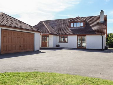A detached house with a tiled roof a garage and a driveway with grass in front at Meadowside in Goonhavern
