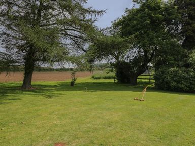 A grassy garden area with croquet equipment and trees in the background at Reybridge House in Lacock