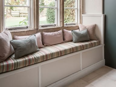 A seating area with cushions by windows at Reybridge House in Lacock