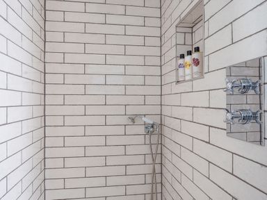 A shower area with tiling and body wash bottles at Reybridge House in Lacock