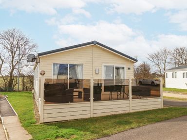 An exterior view of a single-story mobile home with a patio and outdoor furniture at Two Little Ducks in Cayton