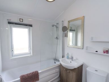 A bathroom with a bathtub shower sink mirror and toilet at Two Little Ducks in Cayton