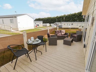 A deck with outdoor seating and a small table set with tea cups at Two Little Ducks in Cayton