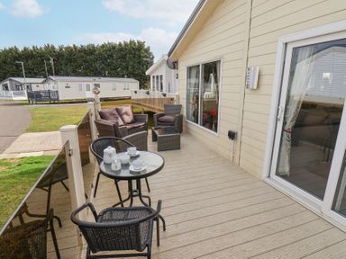 An outdoor deck with patio furniture including a glass table set with teacups and a sofa set at Two Little Ducks in Cayton