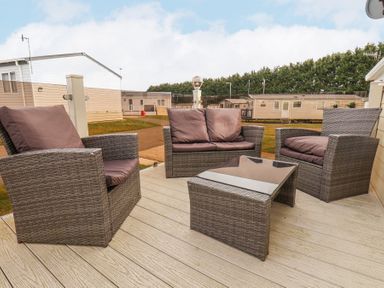 An outdoor patio with wicker chairs and a glass top table at Two Little Ducks in Cayton