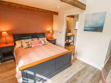 A bedroom with a grey bed frame and nightstands with lamps at The Roost in Porthallow