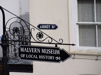 A street sign for Malvern Museum of Local History pointing right near a window with a sign Abbey Rd on the wall at The Escape in Malvern