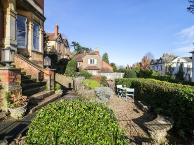 An outdoor garden area with stone steps and green bushes with a small table and two chairs at The Escape in Malvern