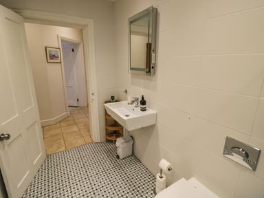 A bathroom with a sink and mirror and a toilet paper holder at The Escape in Malvern