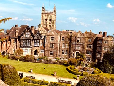 A hotel building with a garden and tower at Abbey Hotel in Malvern
