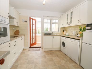 A kitchen with white cabinets a washing machine dishwasher and refrigerator at Dove's Nest in Martham