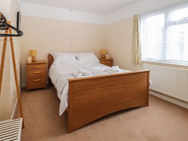 A bedroom with a wooden bed and two nightstands next to a window at Dove's Nest in Martham