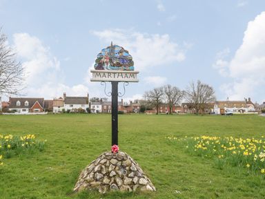 A village green with a signpost reading martham surrounded by daffodils and houses at Dove's Nest in Martham