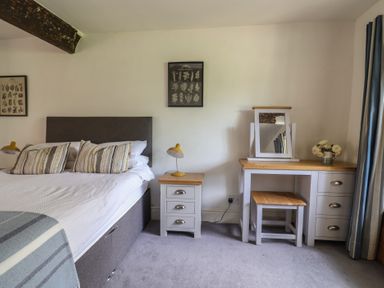 A bedroom with a bed, side table, dressing table and a mirror at Garden View, Wellington