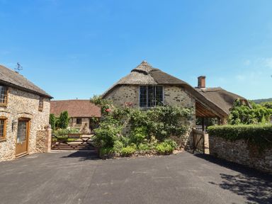A thatched cottage with stone walls and a garden at Garden View in Wellington