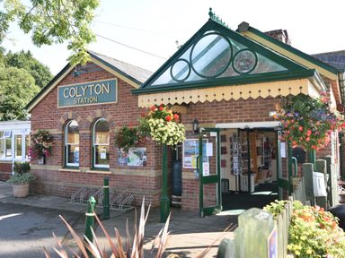 A brick train station building with green framed windows and doors at Colyton Station