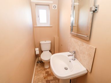 A small bathroom with a toilet sink mirror and window at Anvil Cottage in Appleton Wiske