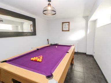 A room with a purple pool table with cues a wall mirror and a framed picture at Anvil Cottage in Appleton Wiske