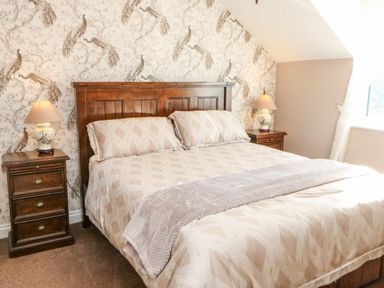 A bedroom with a wooden bed and nightstands with lamps at Anvil Cottage in Appleton Wiske
