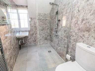 A bathroom with a wall-mounted sink toilet and walk-in shower at Anvil Cottage Appleton Wiske