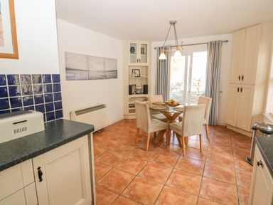 A dining area with a round glass table and four beige chairs on a tiled floor at 1 Closheen Lane Rosscarbery County Cork