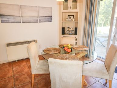 A dining area with a round glass table and four chairs near a sliding glass door at 1 Closheen Lane in Rosscarbery County Cork