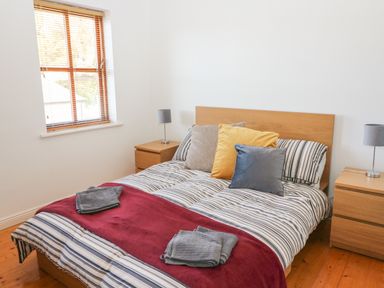 A bedroom with a wooden bed and two bedside tables with lamps at 1 Closheen Lane in Rosscarbery County Cork