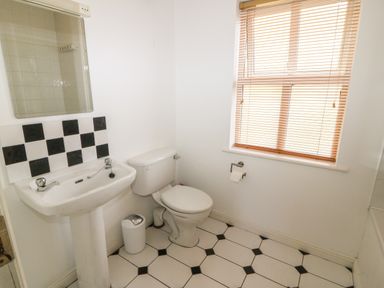 A bathroom with a pedestal sink a toilet a window with blinds and a tiled floor at 1 Closheen Lane in Rosscarbery County Cork