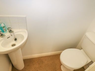 A small bathroom with a white sink and a white toilet on a patterned floor at 1 Closheen Lane in Rosscarbery County Cork