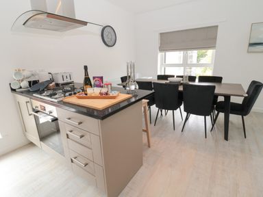 A kitchen with a gas stove and dining table with chairs at Summer Rose in Craster