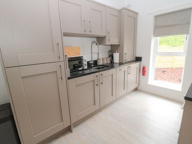 A kitchen with beige cabinets black countertop microwave sink window and fire extinguisher at Summer Rose in Craster