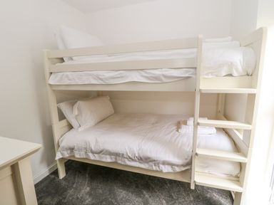 A bedroom with a white bunk bed and white bedding at Summer Rose in Craster