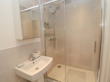 A bathroom with a sink and a shower cubicle with glass doors at Summer Rose in Craster