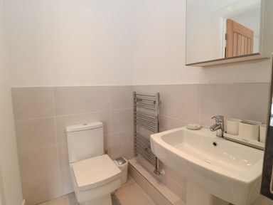 A bathroom with a toilet a sink with toiletries and a towel radiator at Summer Rose in Craster