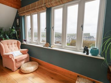 An armchair next to a window with plants and decorative objects on the windowsill at Sandy Combe in West Bay