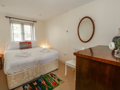 A bedroom with a bed folded towels a dresser with a mirror and a chair at Sandy Combe in West Bay