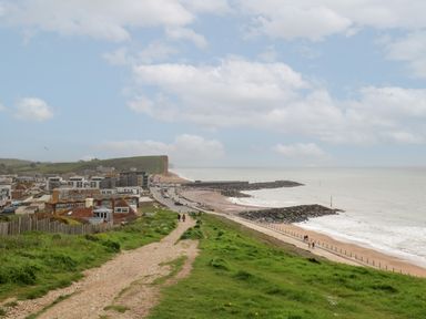 A coastal town with a beach a path leading down to the shore and cliffs in the background at Sandy Combe West Bay