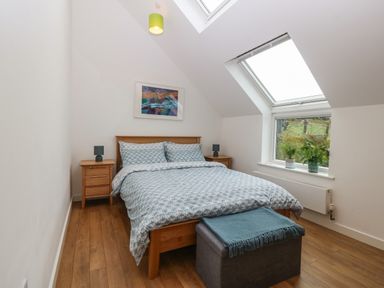 A bedroom with a double bed flanked by wooden nightstands under a skylight window at Hen Gapel in Waunfawr Gwynedd