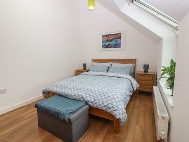 A bedroom with a wooden bed and two bedside tables with lamps at Hen Gapel in Waunfawr Gwynedd