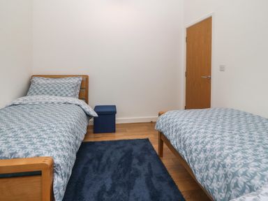 A bedroom with two single beds a blue rug and a wooden door at Hen Gapel in Waunfawr Gwynedd