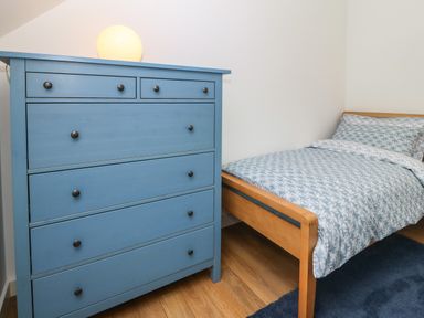 A bedroom with a blue dresser and a wooden bed with patterned bedding at Hen Gapel in Waunfawr Gwynedd