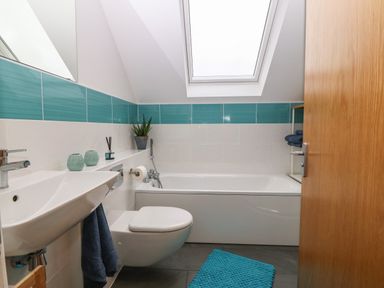 A bathroom with a bathtub sink wall mounted toilet and skylight window at Hen Gapel in Waunfawr Gwynedd