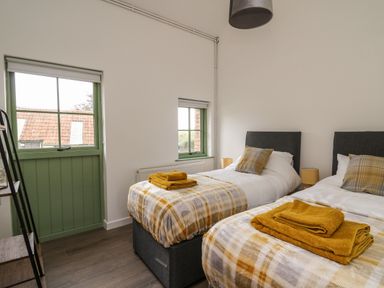 A bedroom with two single beds with plaid blankets and mustard towels at Cwrt y Wennol in Salem near Clydach
