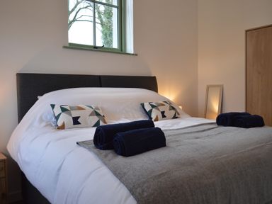 A bedroom with a double bed with white bedding and geometric patterned pillows at Cwrt y Wennol in Salem near Clydach