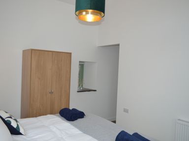 A bedroom with a wooden wardrobe a bed with towels on it and a ceiling lamp at Cwrt y Wennol in Salem near Clydach