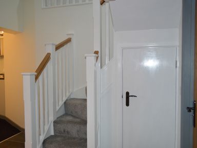 A staircase with gray carpet and white banisters next to a closed white door at Cwrt y Wennol in Salem near Clydach